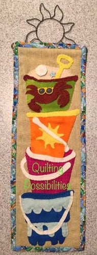 Beach Day Wool Kit is a brightly colored wool applique of a tower of sandpails with beachy appliques and colorful buttons From Patch Abilites & Barnegat Bay Dyeworks
