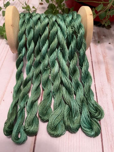 Skeins of hand dyed. variegated #12, #8 and embroidery floss in a medium green with a hint of blue.