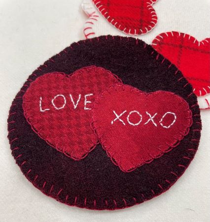 Wool applique mug rug to celebrate Valentine's Day in hand dyed wools. 5 inches