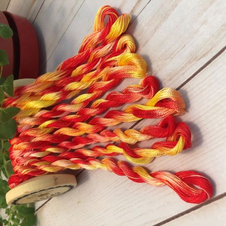 Sunrise hand dyed threads in bright bold colors of red, orange yellow and maybe a hint of pink.