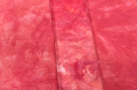 Hand dyed fabrics in a mottled, medium red on flannel, linen and cotton.