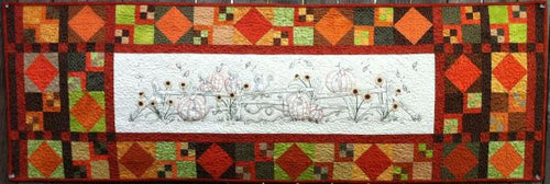 Hand embroidery pattern of pumpkins, sunflowers and a cat along a split rail fence with pieced border in fall colors. 18