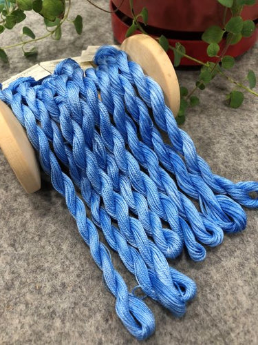Hand dyed threads in a variegated light to medium dark blue in embroidery floss, #12 and #8 pearl cottons.