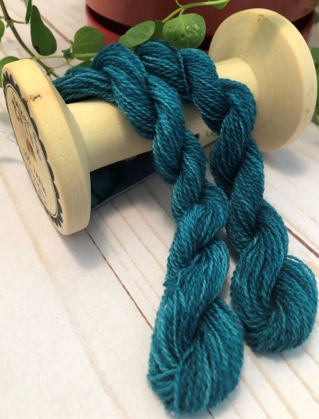 Skeins of hand dyed wool thread in a variegated blue green 