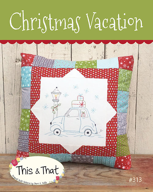 Pattern cover showing a vintage bug type car with gifts on the roof and a lamp post with a candle and holly in a snowstorm made into a pillow with a pieced border.