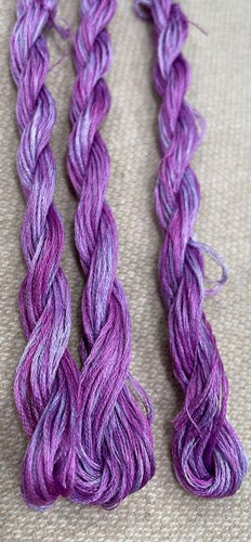 Skeins of hand dyed, six strand, 100% cotton embroidery floss in a variegated grape purple.
