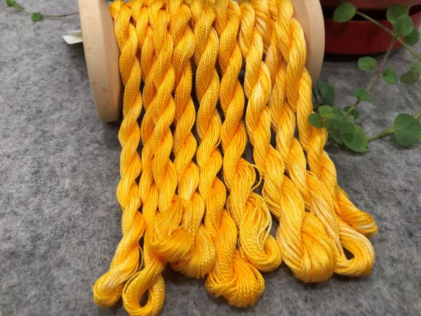 Hand dyed threads in 6 strand embroidery floss, #12 and #8 pearl cottons in a goldish variegated yellow.