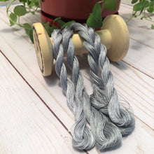 Load image into Gallery viewer, Four strands of a slightly variegated, medium gray, #12 Pearl Cotton draped over a vintage thread spool
