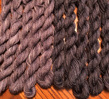 Load image into Gallery viewer, Skeins of two hand dyed wool threads in two gray variegations,  the Grays has  lights to mediums on the left and the Gray Charcoal has mediums to dark. on the right.
