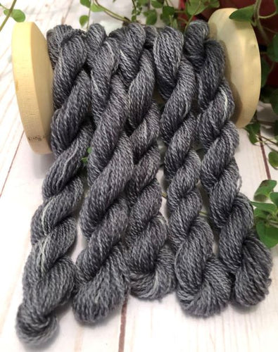 Variegated, hand dyed wool thread from light gray to dark gray.