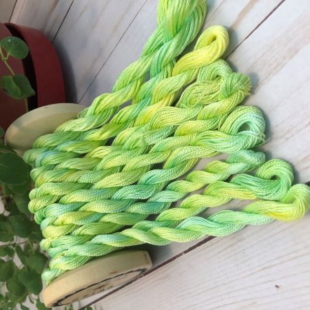 Nine skeins of yellow and green with a hint of blue threads in #12 and #8 pearl cottons and 6 strand embroidery floss .