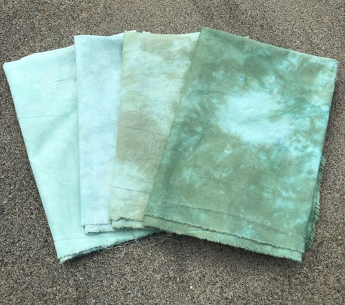 Four hand dyed, mottled, cotton fabrics in shades of the same blue green