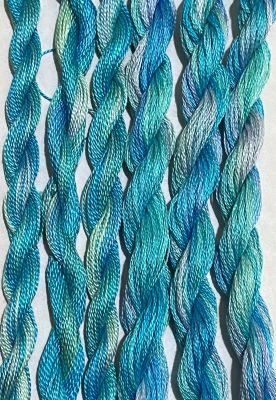 Hand dyed threads in shimmery shades of turquoise, green and a touch of purple