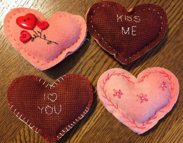 Four stuffed wool hearts two red with sayings 