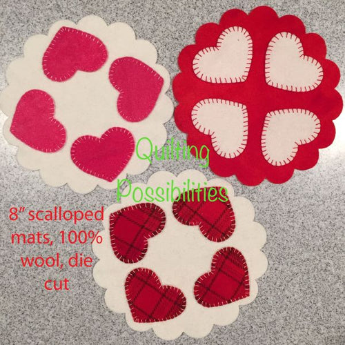 Die cut wool applique hearts on a die cut wool scalloped mat in reds ,  pinks and whites.