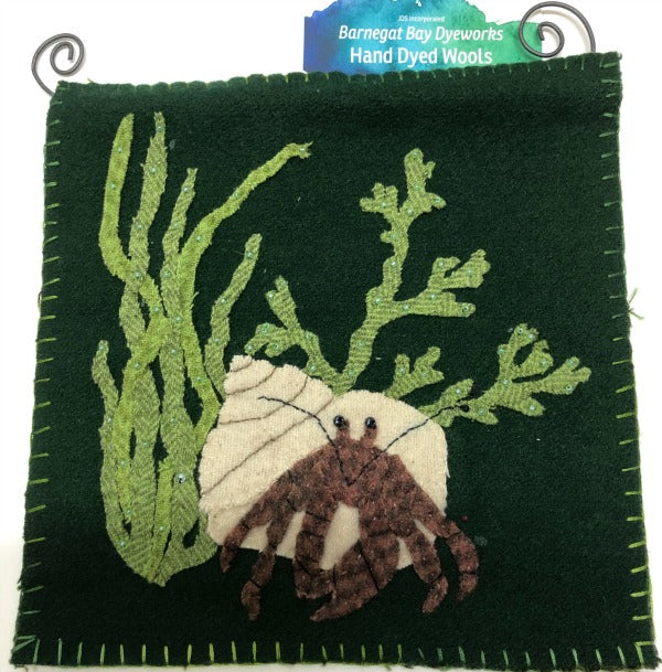 This wool applique hermit crab has found his home in a shell hidden in the seaweed.