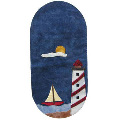 Oval wool applique mat with a lighthouse  and sailboat at one end, moon and cloud in the middle.