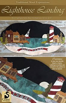 Wool applique pattern cover for Lighthouse Landing with a lighthouse standing watch over a coastal town.