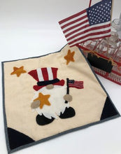 Load image into Gallery viewer, Wool applique gnome dressed as Uncle Sam holding a flag and a star in a 12&quot; wall hanging.

