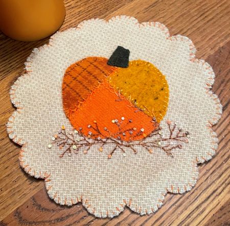 8 inch wool applique mat has a crazy quilted pumpkin on a bittersweet vine.