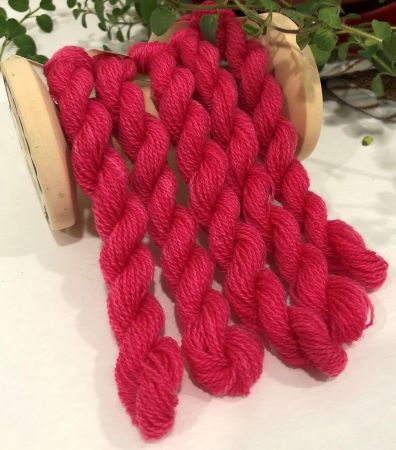 Skeins of hand dyed wool threads in a rich, warm, medium to dark  pink.