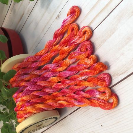 Skeins of hand dyed threads in variegated bright pinks and oranges