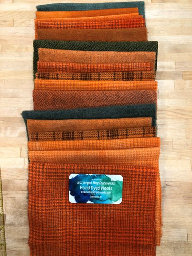 A stack of hand dyed wool in oranges and greens showing three of the wool bundles for a representation of what the bundles will contain.