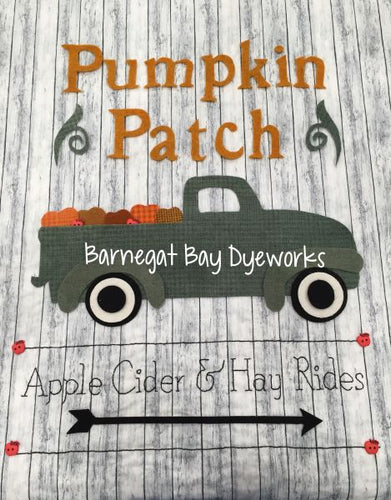 Pumpkin Patch Sign wool applique sample with vintage green truck , Pumpkin Patch words and directional arrow in wool on a cotton woodgrain background.