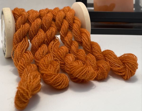 Skeins of hand dyed wool thread in a warm orange, the color of pumpkin pie.