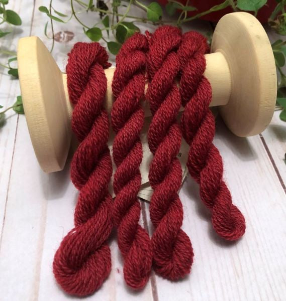 Skeins of hand dyed wool thread in a medium dark red.