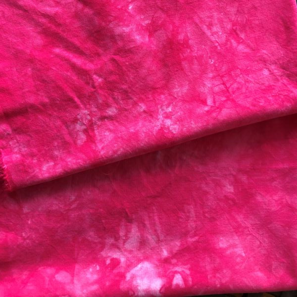 Hand dyed cotton fabric in a mottled bright red with a pink tone
