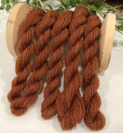 Skiens of hand dyed wool threads in a variegated, soft, medium dark brown with a hint of red.