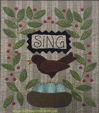 Load image into Gallery viewer, Sing wool applique on cotton wall hanging showing our wools in our kit with a robins nest with eggs, a robbin and greenery on both sides with the word &quot;Sing&quot; embroidered in a small banner above the robin.
