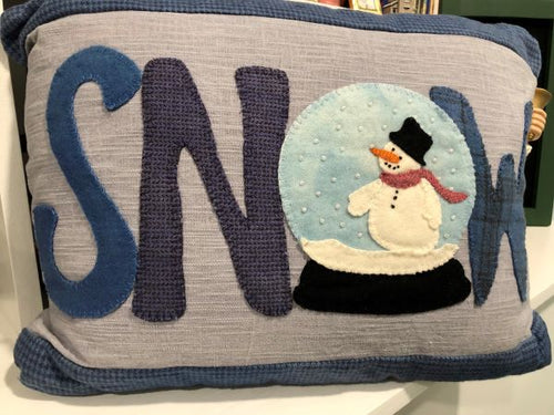 A kit to make a wool applique framed piece with SNOW spelled out and the O is a snow globe with a snowman inside