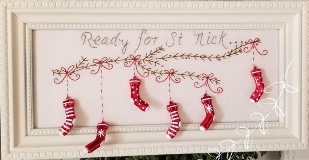Pattern for hand embroidered evergreen bough with stocking charms hanging along it.  Ready For St Nick is hand stitched above.