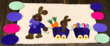 Load image into Gallery viewer, Wool applique runner of a mama rabbit pulling her bunny and Easter eggs in wooden wagons stitched  in our hand dyed wools.
