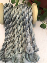 Load image into Gallery viewer, This picture shows our three different hand dyed gray colored threads together - first two on the left Gray to Black are the darkest , middle four are Gray Medium and are the lightest of the three grays and the four on the right are Stormy Gray, medium grays.
