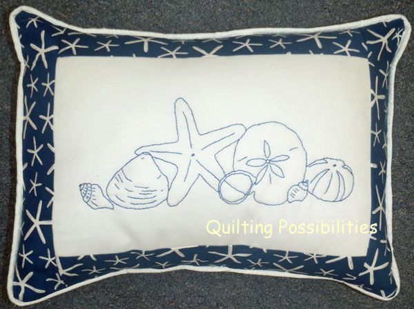 A pattern for a small pillow done in hand embroidery with a starfish, sand dollar, sea urchin, slipper shell, welks and a clam shell.