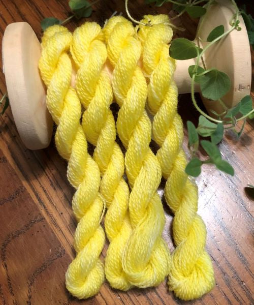 Skeins of a warm, light yellow, hand dyed wool thread.